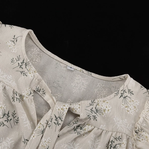 Detailed close-up of ruffle collar and drawstring neckline on floral print shirt