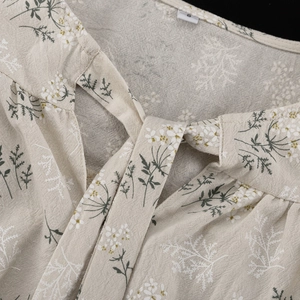 Detail of floral ruffle blouse neckline with ribbon tie and soft cotton texture