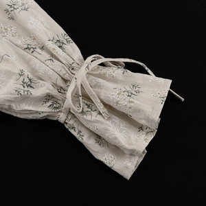 Detail of ruffled cuff with drawstring tie and green floral print on beige fabric