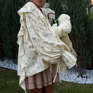 Floral ruffle blouse with lantern sleeves and lace-up cuffs on an outdoor background