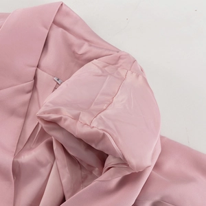 Detailansicht des rosa Anzugkragens mit Seidenfutter und Größenetikett S auf Stoff