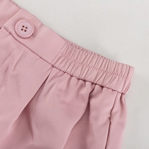 Detail einer rosa Anzughose mit mattem Knopf und elastischem Bund für Komfort