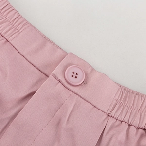 Detail der rosa Anzughose mit elastischem Bund und farblich passendem Knopfverschluss