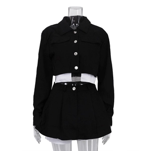Detalle de chaqueta corta negra con botones plateados y diseño de patchwork blanco