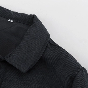 Detalle de cuello de pana negra con textura vertical y pequeña etiqueta blanca talla S