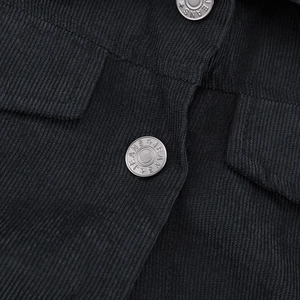 Detalle macro de chaqueta de pana negra con textura y botones metálicos tipo vaquero