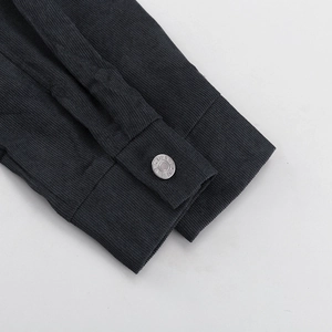 Detalle del puño de pana con botón metálico plateado grabado con inscripción de jeans