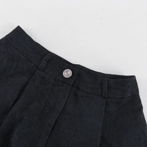 Detalle de cintura de pana gris oscuro con nervaduras y botón metálico grabado