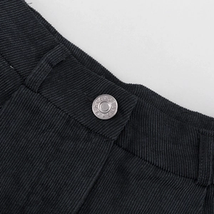 Primer plano de tela de pana negra con un botón de metal plateado grabado con JEANS
