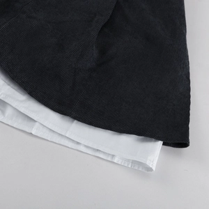 Primer plano del diseño de capas en contraste con pana negra y forro blanco liso