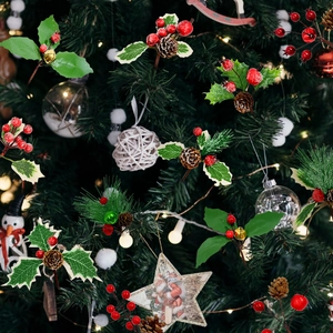 Artificial Christmas berries with pine cones and holly leaves on festive tree background