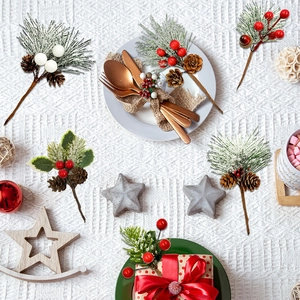Close-up of Christmas DIY picks with snowy pine needles and red berries on white cloth