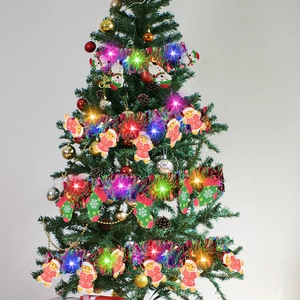 Close-up of LED tinsel garland with snowman and gingerbread charms on a Christmas tree