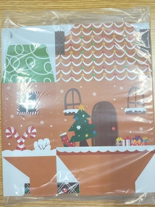 Unassembled Christmas gingerbread house gift box in transparent plastic packaging