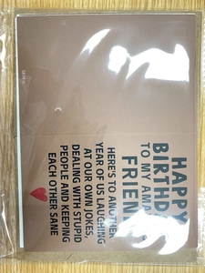 Close-up of a brown paper birthday card with black text and a small red heart
