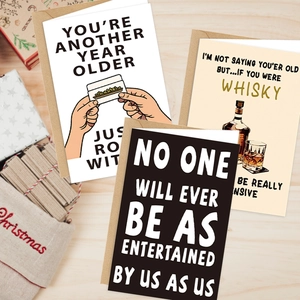 Close-up of three funny greeting cards with kraft envelopes on a wooden table