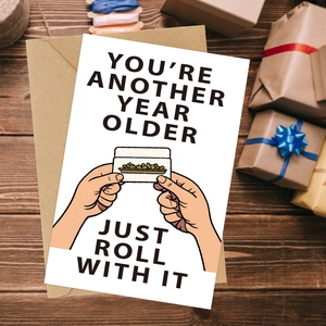 Funny 'Just Roll With It' greeting card with kraft envelope on a wooden table setup
