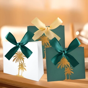 Detail of white and green gift boxes with gold palm trees and silk ribbons