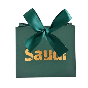 Detail of dark green Saudi gift bag with a gold palm tree logo and satin ribbon bow