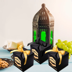 Detail of black Umrah Mubarak gift boxes with gold Kaaba print and decorative satin ribbons