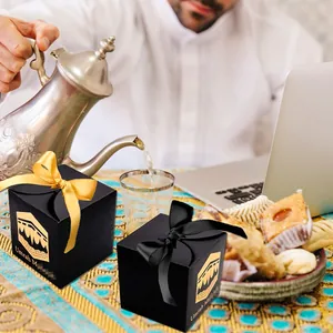 Close-up of black Umrah Mubarak gift boxes with gold foil Kaaba motifs and silk ribbons