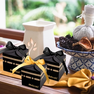 Elegant black gift box with gold foil hollow patterns and satin ribbon bow decoration