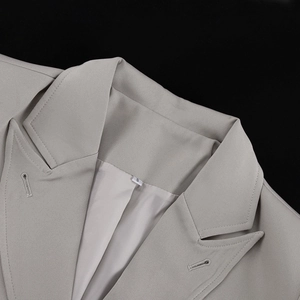 Detail shot of notched lapels and fine stitching on a light grey women's blazer