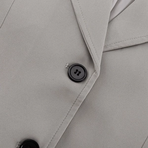 Detail of light grey blazer fabric showing fine texture and black four-hole buttons