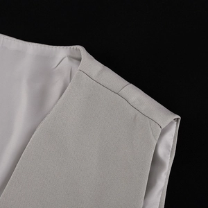 Macro shot of light gray vest shoulder seams with smooth stitching and fabric texture