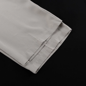 Detailed close-up of light gray trousers hem with fine woven texture and neat stitching