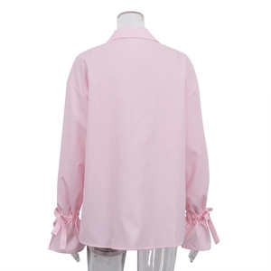 Detail der gestreiften rosa Bluse mit Schleifen an den Manschetten und gerafften Ärmeln