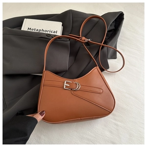 Brown leather crescent bag detail with metal buckle strap on a black blazer jacket