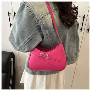 Side view of a bright pink crescent baguette bag with silver buckle on a model