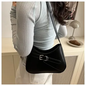 Detail of minimalist black crescent bag with silver buckle strap in a lifestyle setting