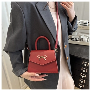 Chic red bow accent crossbody bag styled with a dark grey blazer for women