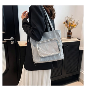 Detail of light blue pleated tote bag featuring a mesh pocket and metallic textured fabric