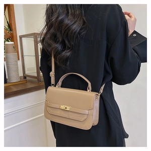 Detail of a chic cream crossbody bag with gold metal hardware on a person's shoulder