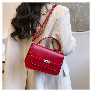 Detail of red vintage leather handbag with gold metal clasp on a beige blazer