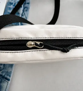 Macro detail of the smooth metal slider and black zipper on the beige canvas cosmetic bag