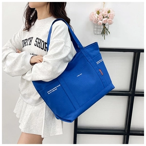 Detailansicht einer geräumigen königsblauen Canvas-Tasche mit weißer Aufschrift und Seitenfach
