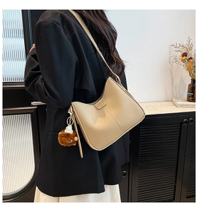 Détail du sac bandoulière beige demi-lune en cuir mat avec breloque ours en peluche