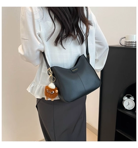 Détail d'un sac seau noir mat avec lettrage doré et charmant pendentif petit monstre