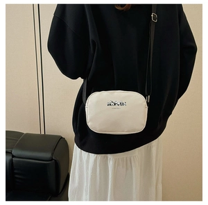 Close-up of a cream canvas panda baby crossbody bag styled with casual outfit