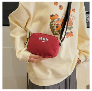 Model wearing a small red nylon travel makeup bag with panda print and black strap