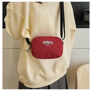 Detail of red canvas crossbody camera bag featuring panda illustration and adjustable strap