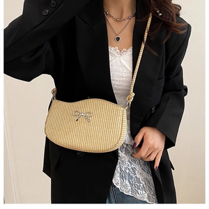 Detail of beige woven straw shoulder bag with a silver metal bow accent for women