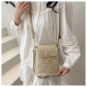 Détails de broderie florale rose et texture tissée sur un sac bandoulière en paille
