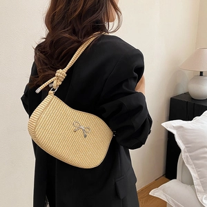 Minimalist straw bow shoulder bag for women styled with a black blazer in a cozy setting
