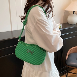 Emerald green woven underarm bag with silver bow accent and adjustable knotted strap