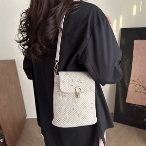 Sac seau tissé avec broderie florale et fermoir doré présenté dans un décor de vie